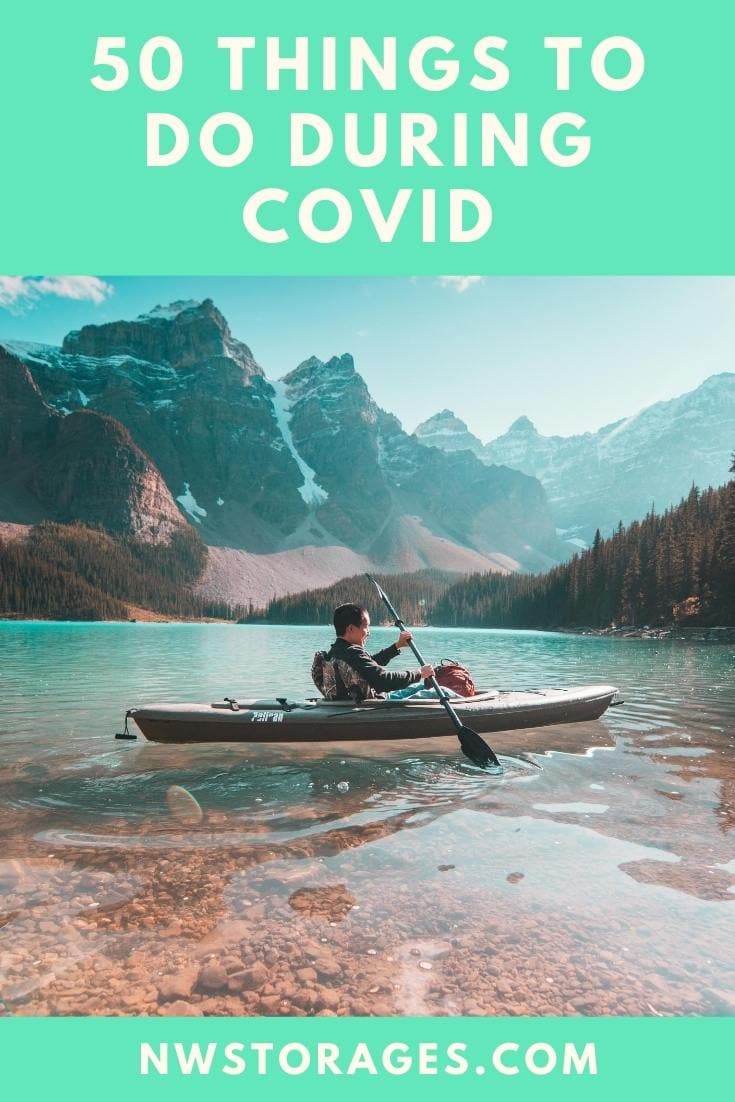 A person in a kayak on a lake with mountains in the background.